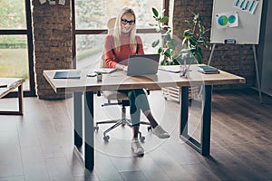 Full body photo of successful charming woman company owner sit table work laptop do startup project wear red turtleneck