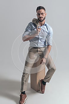 Full body picture of confident man with jacket over shoulder posing