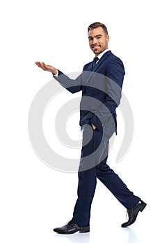 full body picture of elegant businessman holding hand up and showing