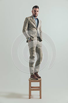 Full body picture of handsome man in his forties standing on wooden chair