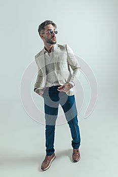 Full body picture of man with hand in pockets looking to side