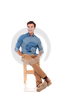 Full body picture of relaxed seated man looking to side