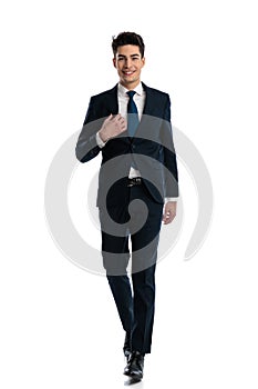 full body picture of sexy man walking and adjusting elegant suit