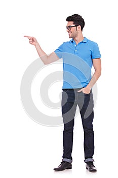 Full body picture of a smiling casual man pointing to side