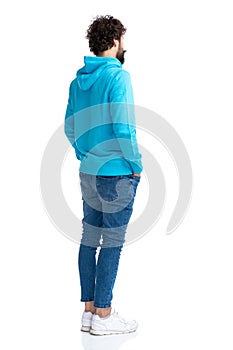 Full body picture of unshaved guy holding hands in pockets