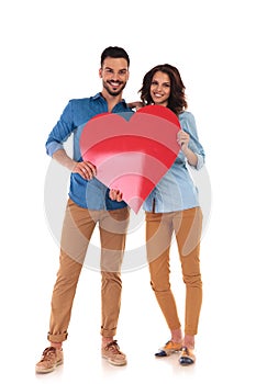 Young in love couple holding big red heart
