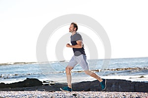 Full body portrait of active man running by beach