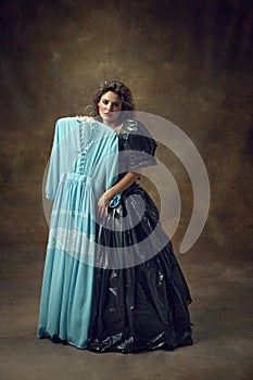 Full body portrait of attractive young woman wearing, black balldress made of garbage bags holding blue midi dress and