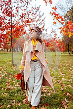 Full body portrait of beautiful woman wearing stylish warm yellow, beige clothes in autumn park. Female fall fashion