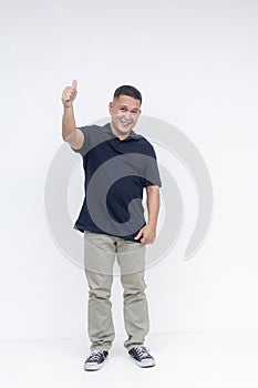 Full-body portrait of a cheerful middle-aged Asian man giving a thumbs up sign, standing against a white background