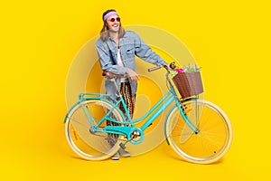 Full body portrait of cool young man bicycle look empty space wear denim shirt isolated on yellow color background