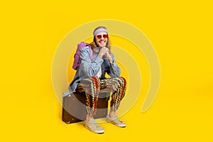 Full body portrait of cool young man sit valise empty space ad wear denim shirt isolated on yellow color background
