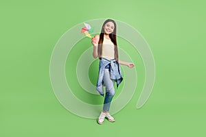 Full body portrait of cute cheerful girl arm hold spinner toothy smile isolated on green color background