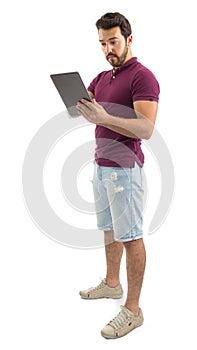 Full body portrait of friendly man. Digital tablet. He is wearing a magenta polo shirt and shorts jeans..