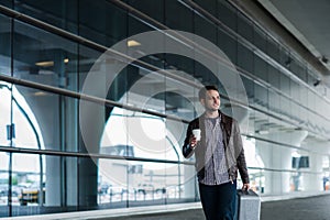 Full body portrait of a happy male traveler walking with bags and coffee