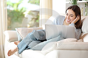 Full body portrait of a happy woman using laptop at home photo