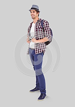 Full body portrait of Man standing with grey background and backpack and camera