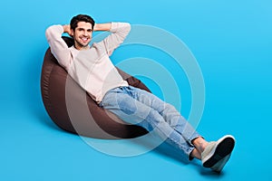 Full body portrait of nice young man sit chill beanbag wear beige sweatshirt isolated on blue color background
