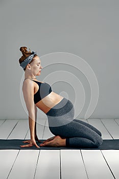 Full Body Portrait Of Pregnant Woman Doing Yoga On Exercise Mat.  on gray background