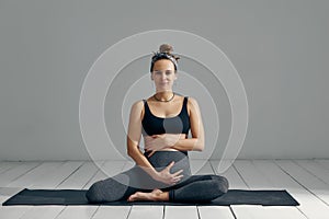 Full Body Portrait Of Pregnant Woman Doing Yoga On Exercise Mat.  on gray background