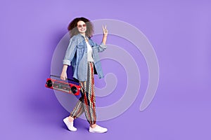 Full body portrait of pretty young woman boombox show v-sign walk empty space wear denim shirt isolated on purple color