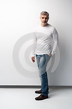 Full body portrait of relaxed mature man standing over white background.