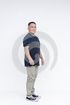 Full body portrait of a self-assured middle-aged Asian man in casual attire standing against a white background