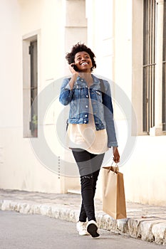 African woman walking on the street with shopping bags and mobile phone