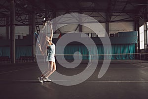 Full body portrait of young girl tennis player in action in a tennis court indoor