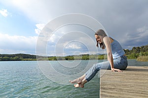 Woman resting sitting in a pier looking at lake