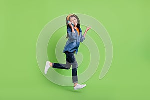 Full body profile photo of angry little girl run talk telephone wear hoop jeans footwear isolated on green background