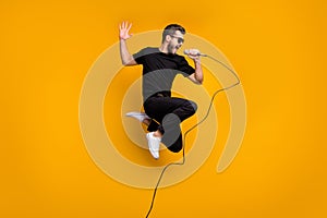 Full body profile photo of crazy hipster guy jumping high holding microphone music lover singing favorite song wear sun