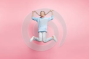 Full body profile photo of pretty little lady jumping high holding cool long braids in hands enjoy sunny weekend wear