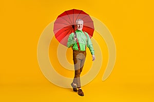 Full body profile side photo of aged man happy positive smile go step spring rainy parasol isolated over yellow color