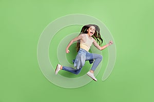 Full body profile side photo of young girl happy positive smile jump go walk run hurry isolated over green color