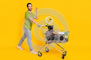 Full body profile side photo of young man go purchase items garage-sale show okey symbol isolated over yellow color