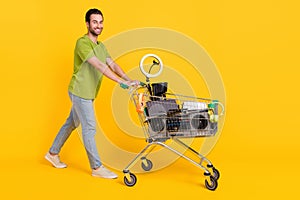 Full body profile side photo of young man go walk trolley shop customer purchase swap thrift isolated over yellow color