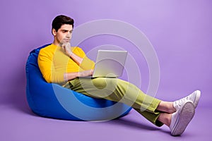 Full body profile side photo of young man serious think look laptop programmer sit chair bean  over violet color