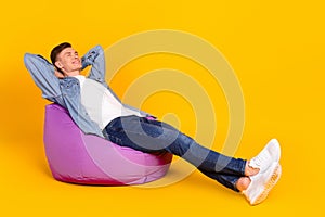 Full body profile side photo of young man sit purple chair hands behind head drowse isolated over yellow color