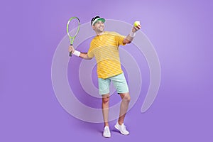 Full body profile side photo of young sporty man happy positive smile play tennis isolated over purple color background