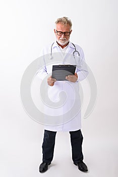 Full body shot of handsome senior bearded man doctor standing wh
