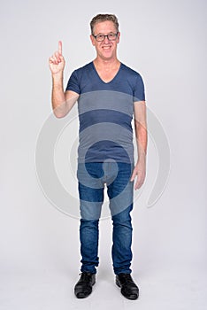Full body shot of happy mature man pointing up against white background