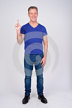 Full body shot of happy mature man pointing up against white background