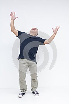 Full body shot of a middle-aged Asian man screaming loudly with his arms up in the air, against a white backdrop