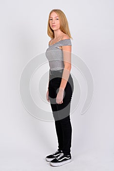 Full body shot profile view of young beautiful blonde teenage girl looking at camera