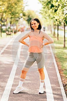 Full body shot of a smiling sporty mid age woman ready to run on the street.