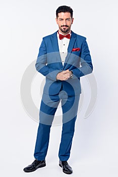 Full body shot of young handsome bearded businessman in blue suit