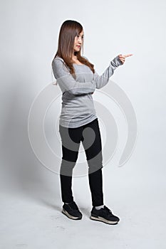 Full body side view of beautiful young asian woman pointing
