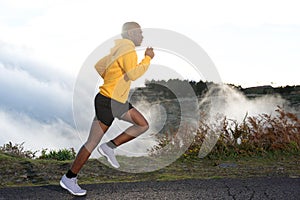 Full body side of young black man road running in nature