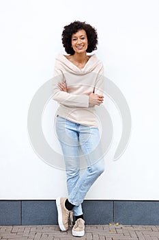 Full body smiling african american woman with arms crossed against white wall